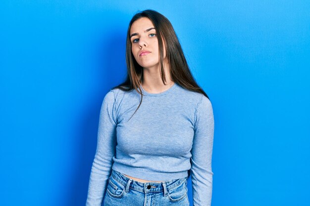 Young brunette teenager wearing casual sweater relaxed with serious expression on face simple and natural looking at the camera