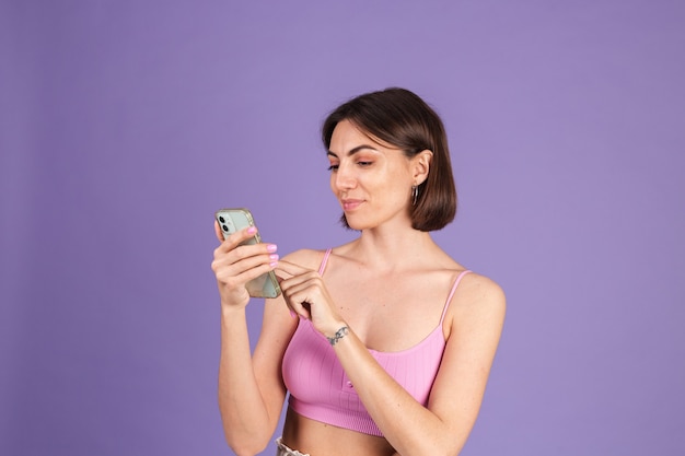 Young brunette in top isolated on purple wall