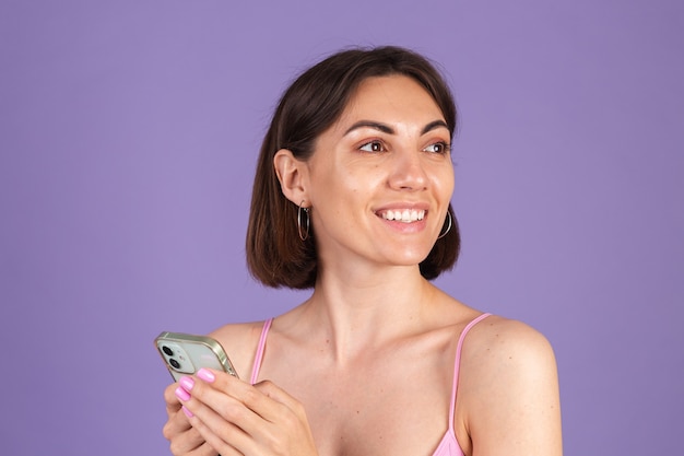 Young brunette in top isolated on purple wall