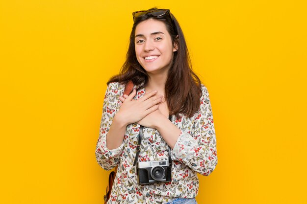 Young brunette traveler woman has friendly expression, pressing palm to chest. love concept