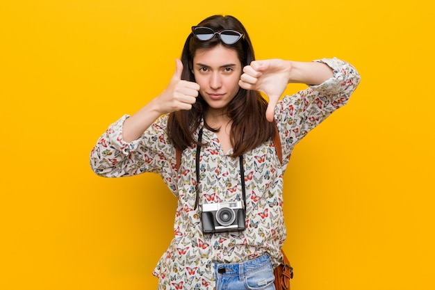 Young brunette traveler woman showing thumbs up and thumbs down