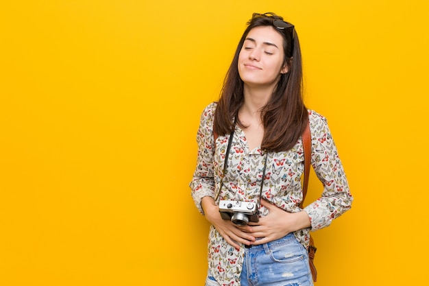 Young brunette traveler woman touches tummy, smiles gently, eating and satisfaction concept.