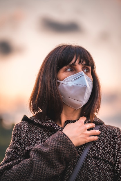 Photo a young brunette with a mask on a sunset. first walks of the uncontrolled covid-19 pandemic