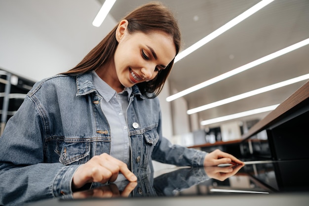 Young brunette woman choosing new electric stove in a hypermarket