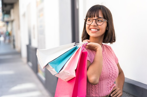 Young brunette woman in the city holding shopping bags and looking back