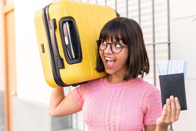 Young brunette woman in the city in vacation with suitcase and passport