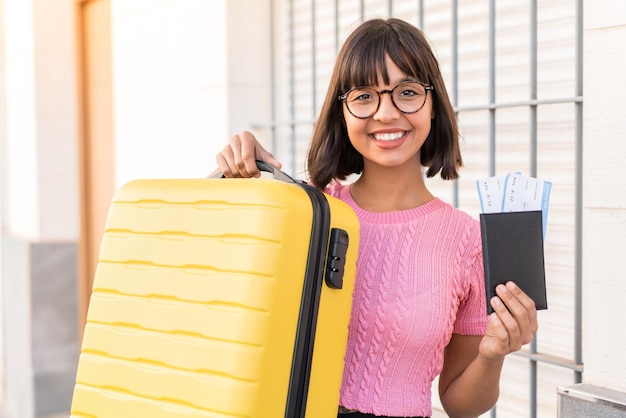 여행 가방과 여권으로 휴가를 보내고 있는 도시의 젊은 갈색 머리 여자