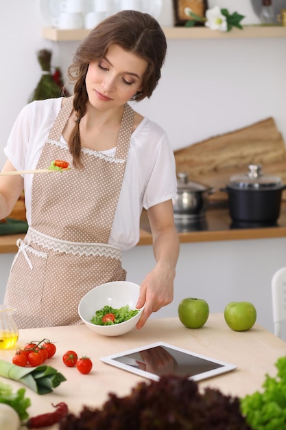 Young brunette woman cooking in kitchen. Housewife holding wooden spoon in her hand. Food and health concept.