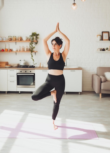 A young brunette woman does yogafitnesssports at home