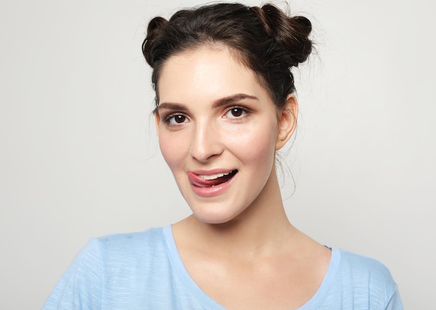 Young brunette woman dressed casually making faces at camera sticking out her tongue