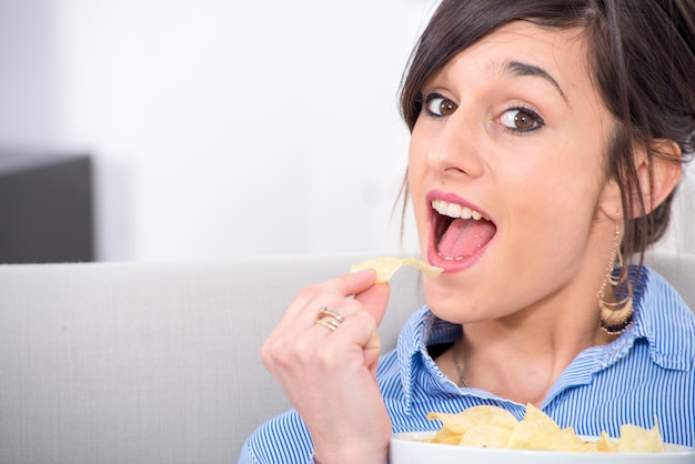 写真 チップを食べる若いブルネットの女性