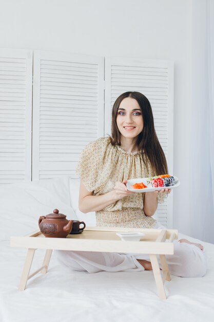 Young brunette woman eating sushi