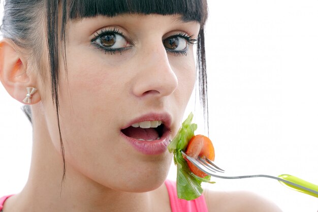 Young brunette woman eats salad, close up