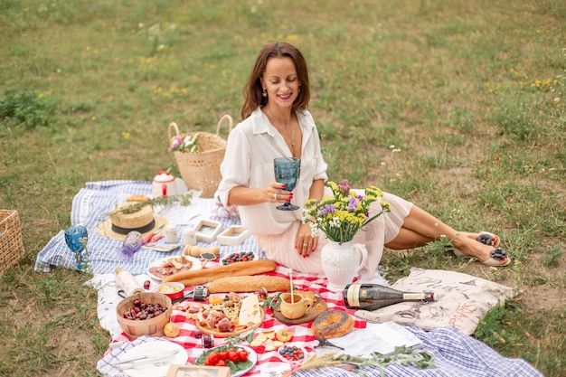 Foto la giovane donna castana gode del picnic all'aperto su prato inglese verde.