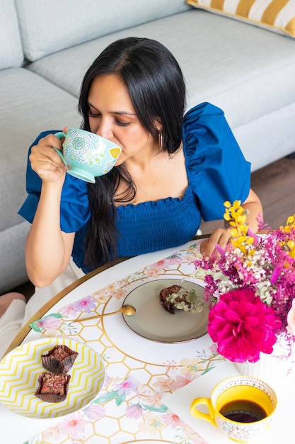 Young brunette woman enjoys eating sweets with coffee