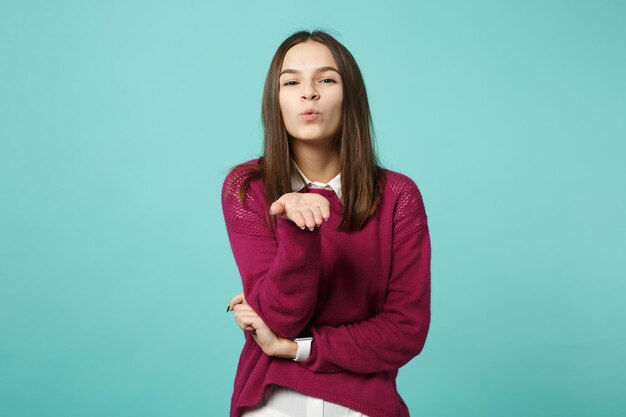 Young brunette woman girl in casual clothes posing isolated on blue wall background studio portrait. people sincere emotions lifestyle concept. mock up copy space. looking camera blow send air kiss