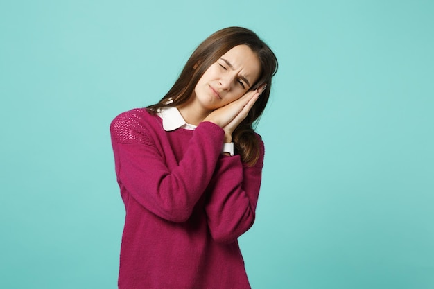 Young brunette woman girl in casual clothes posing isolated on blue wall background studio portrait. People sincere emotions lifestyle concept. Mock up copy space. sleep with folded hands under cheek.