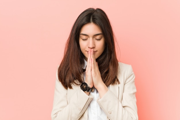 Young brunette woman holding hands in pray near mouth, feels confident.