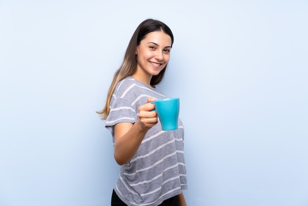 Giovane donna castana che tiene tazza di caffè calda