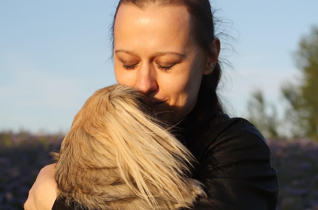 夏の自然の背景に屋外で小さな犬ペキニーズを保持している若いブルネットの女性