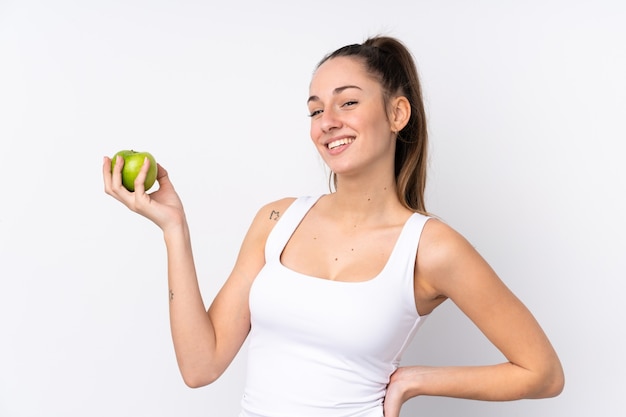Молодая брюнетка женщина над изолированной белой стеной с яблоком и счастливым