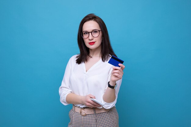 A young brunette woman makes an order online using her phone and bank card