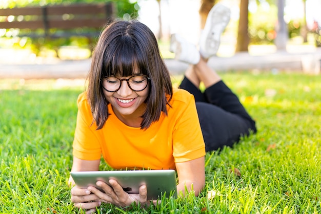 Young brunette woman at outdoors holding a tablet