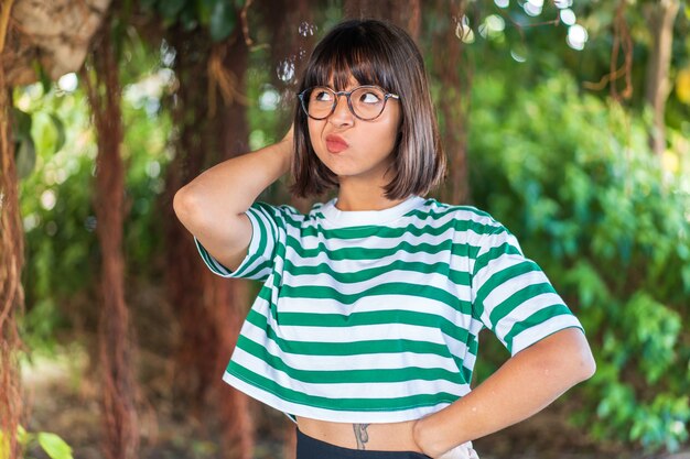 Photo young brunette woman at outdoors in a park having doubts