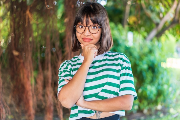 Young brunette woman at outdoors in a park thinking