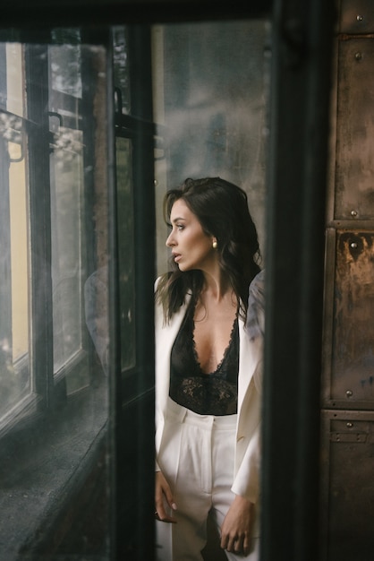 Young brunette woman posing in a suit by the window