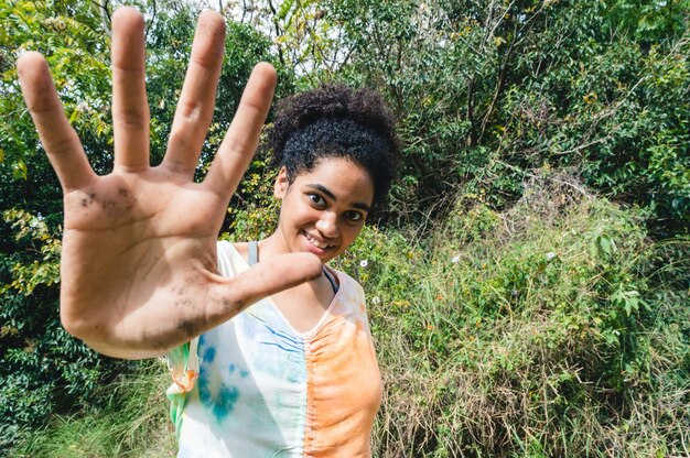 Young brunette woman in public park smiling showing her hand full of dirt