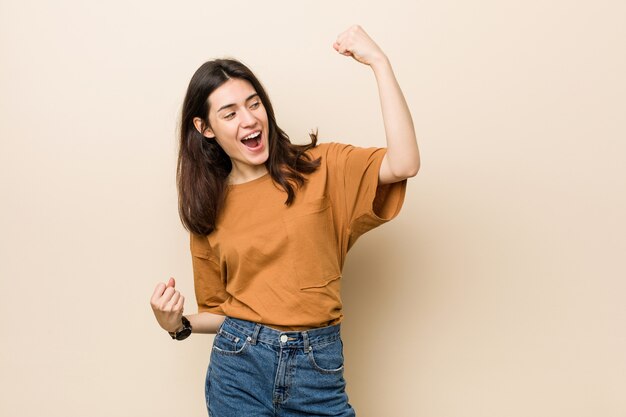 Young brunette woman raising fist after a victory, winner concept.