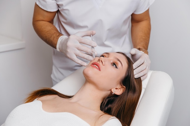 Young brunette woman receiving plastic surgery injection on her face