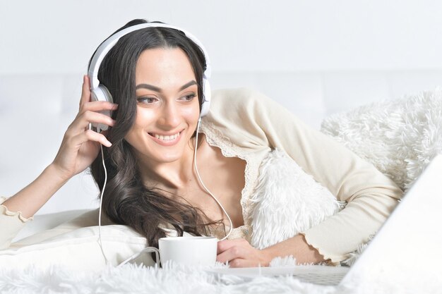 Young brunette woman relaxing in bed using laptop