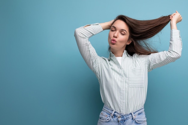 Young brunette woman in shirt with healthy silk hair on studio background