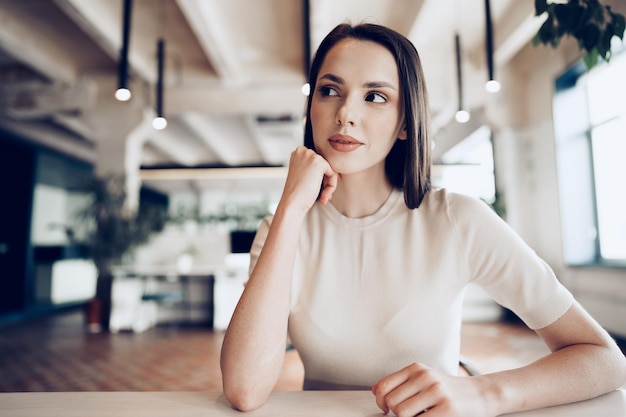 Foto giovane donna bruna seduta al tavolo in ufficio