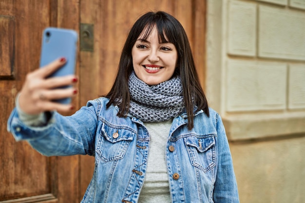 家の入り口で自撮り写真を撮って笑っている若いブルネットの女性