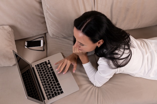 Young brunette woman using a laptop on the sofa