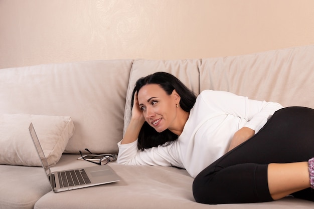 Young brunette woman using a laptop on the sofa