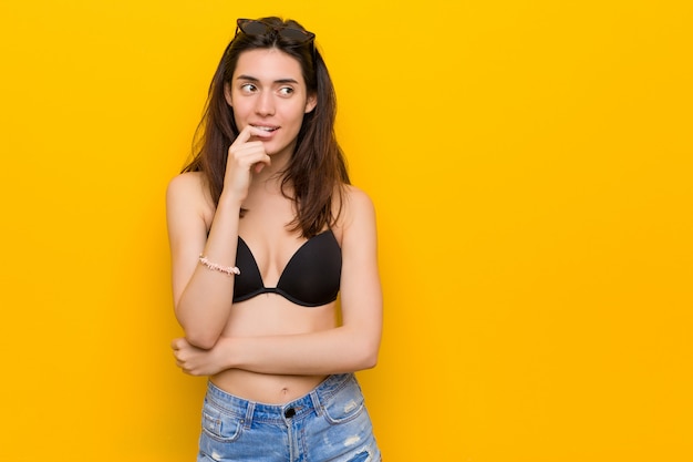 Young brunette woman wearing a bikini relaxed thinking about something 