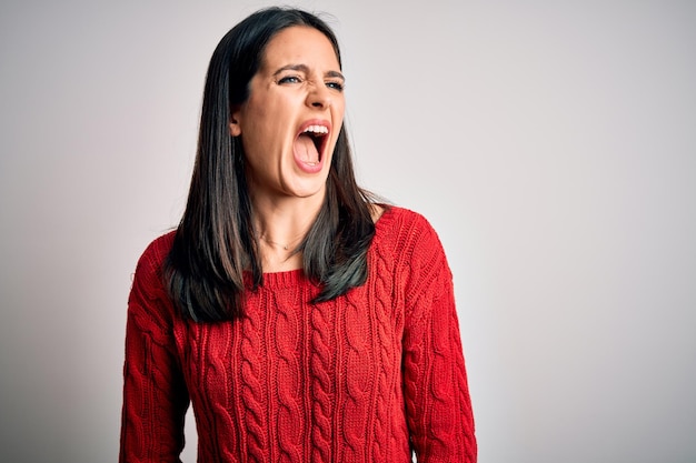 Young brunette woman with blue eyes wearing casual sweater over isolated white background angry and mad screaming frustrated and furious shouting with anger Rage and aggressive concept