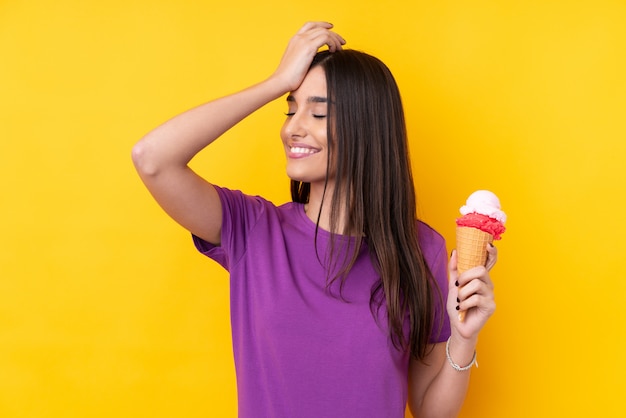 Young brunette woman with a cornet ice cream over isolated yellow wall has realized something and intending the solution