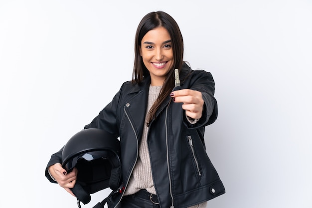 Young brunette woman with a motorcycle helmet and holding a key over isolated white wall