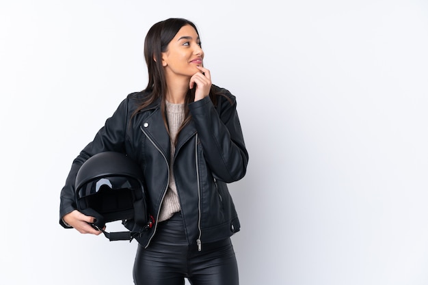 Young brunette woman with a motorcycle helmet thinking an idea and looking side