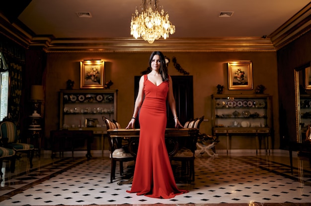 Young brunette woman with a red dress in the living room