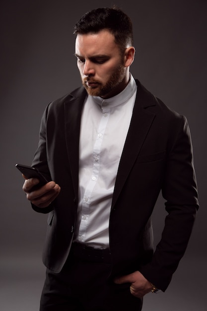 A young brutal businessman writes a message on a smartphone