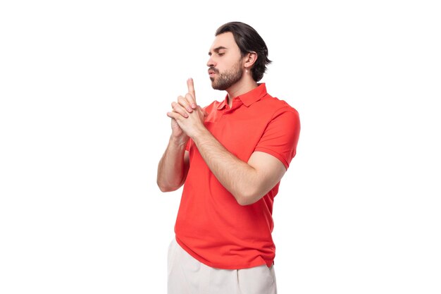 Young brutal caucasian brunette man with a beard wearing a corporate color tshirt on a studio