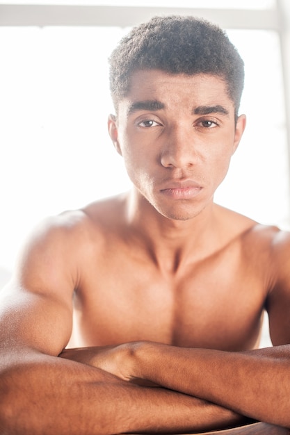 Photo young and brutal. handsome young  afro-american man sitting on the chair and looking at camera