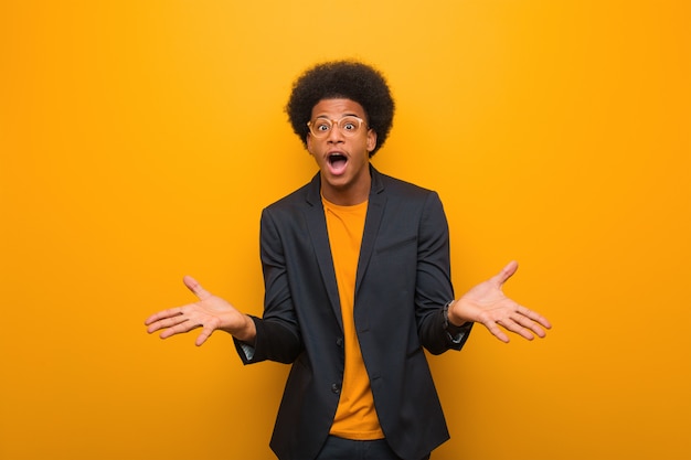 Young business african american man over an orange wall celebrating a victory or success