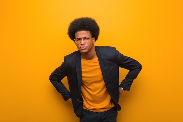 Uomo afroamericano di giovani affari sopra una parete arancio che rimprovera qualcuno molto arrabbiato